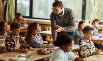 teacher talking to student at desk